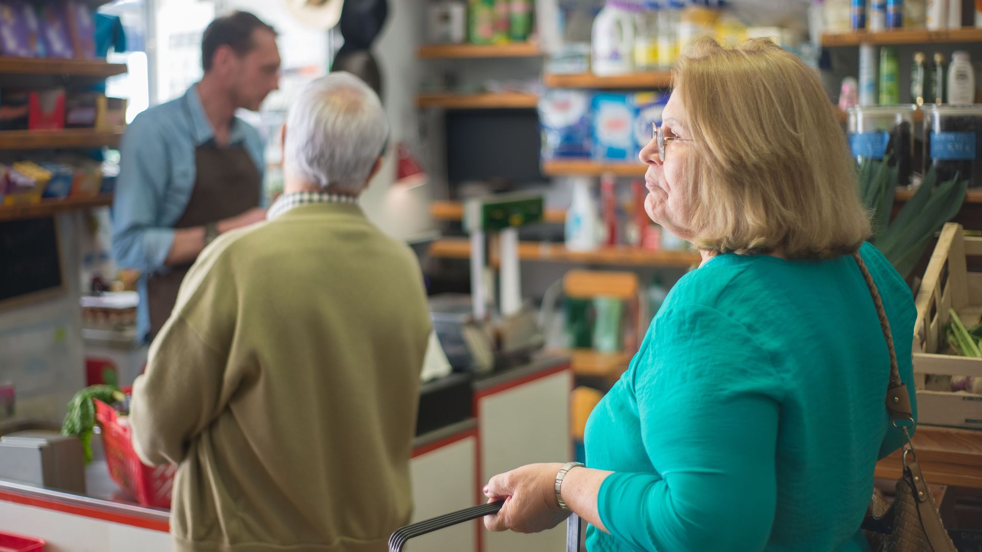 Senior woman with basket shopping in a cozy Portugal grocery store.