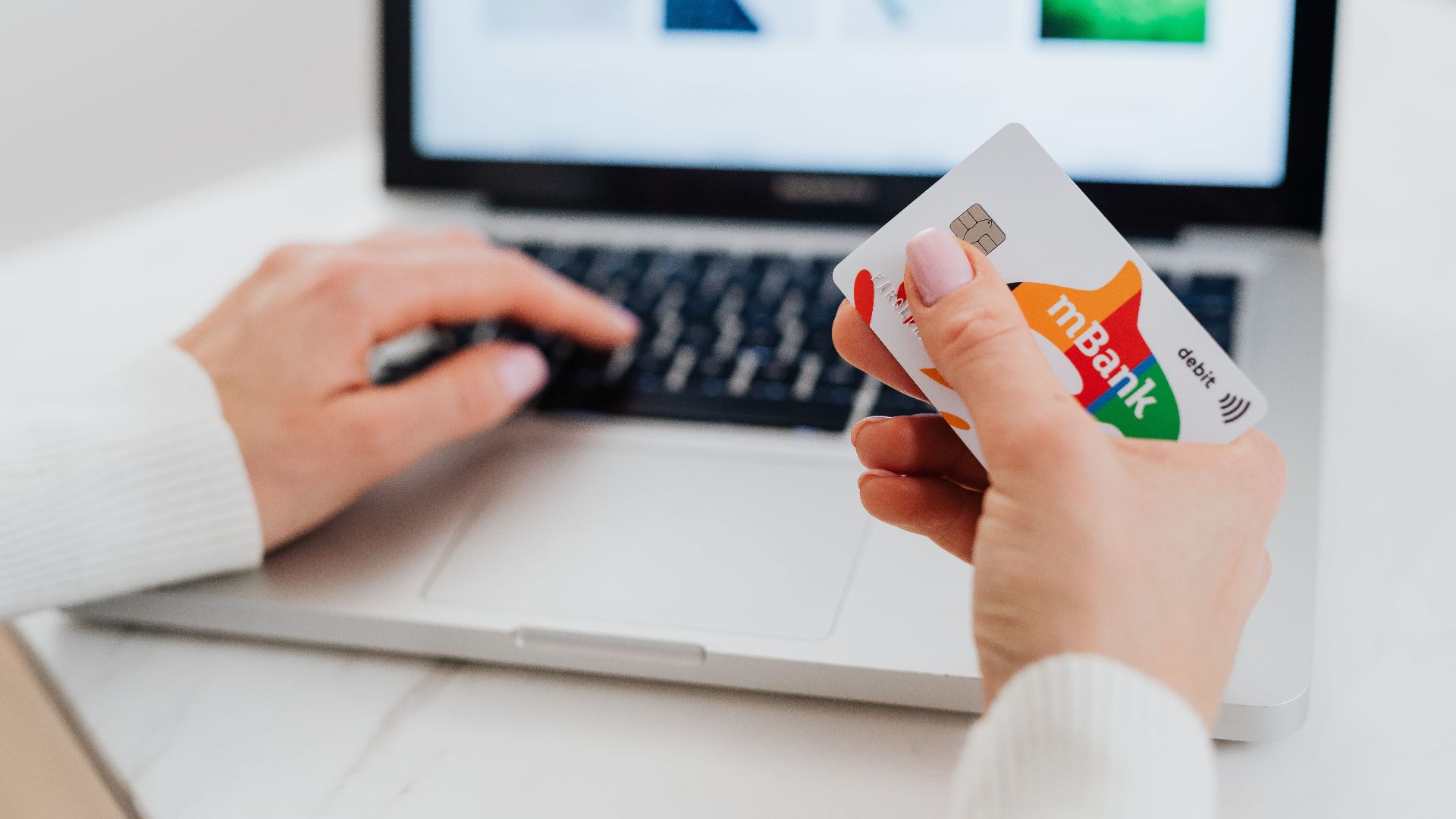Close-up of hands using a laptop and holding a credit card for an online transaction.