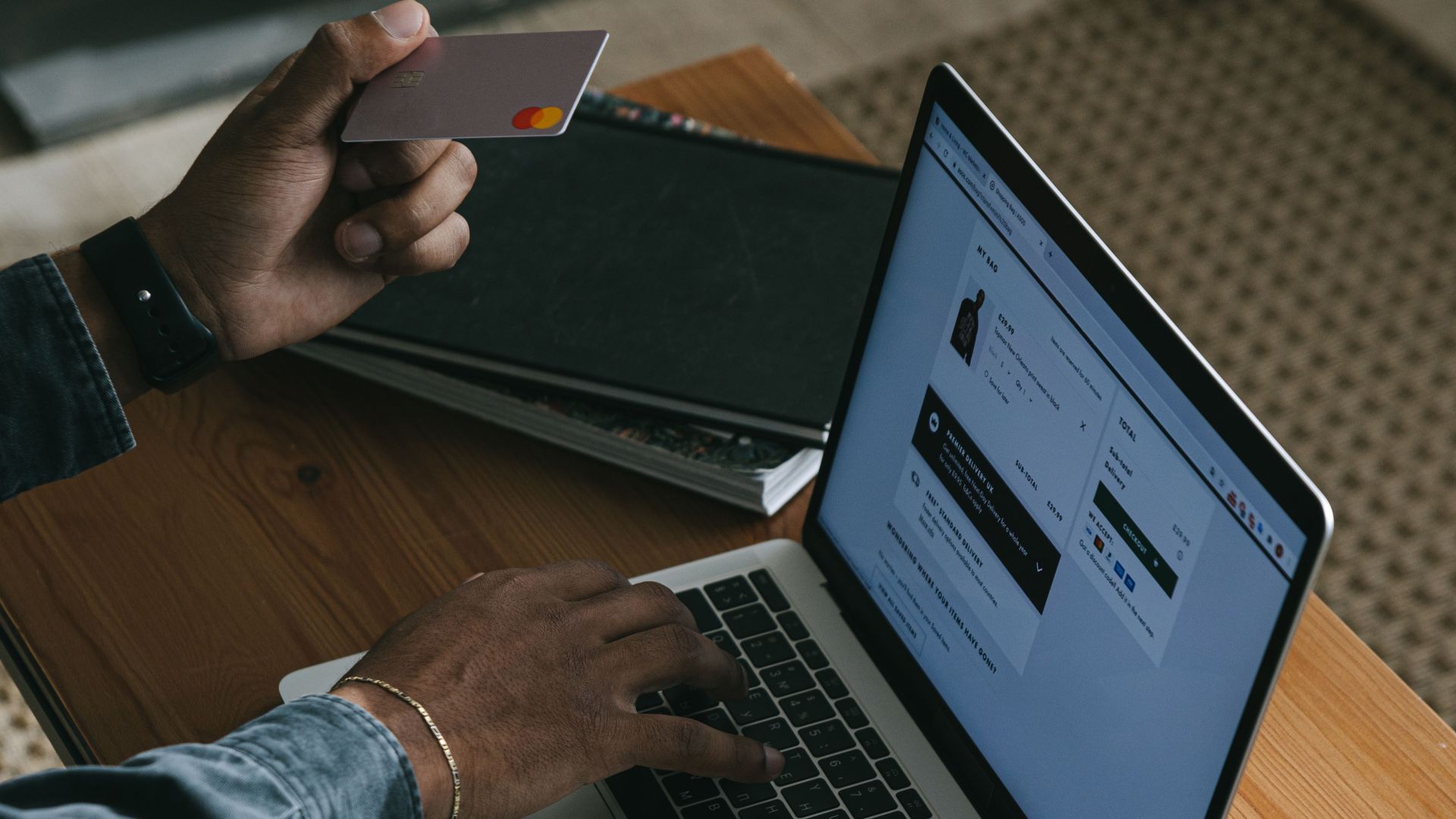 Person using a laptop for online shopping with a credit card in hand.
