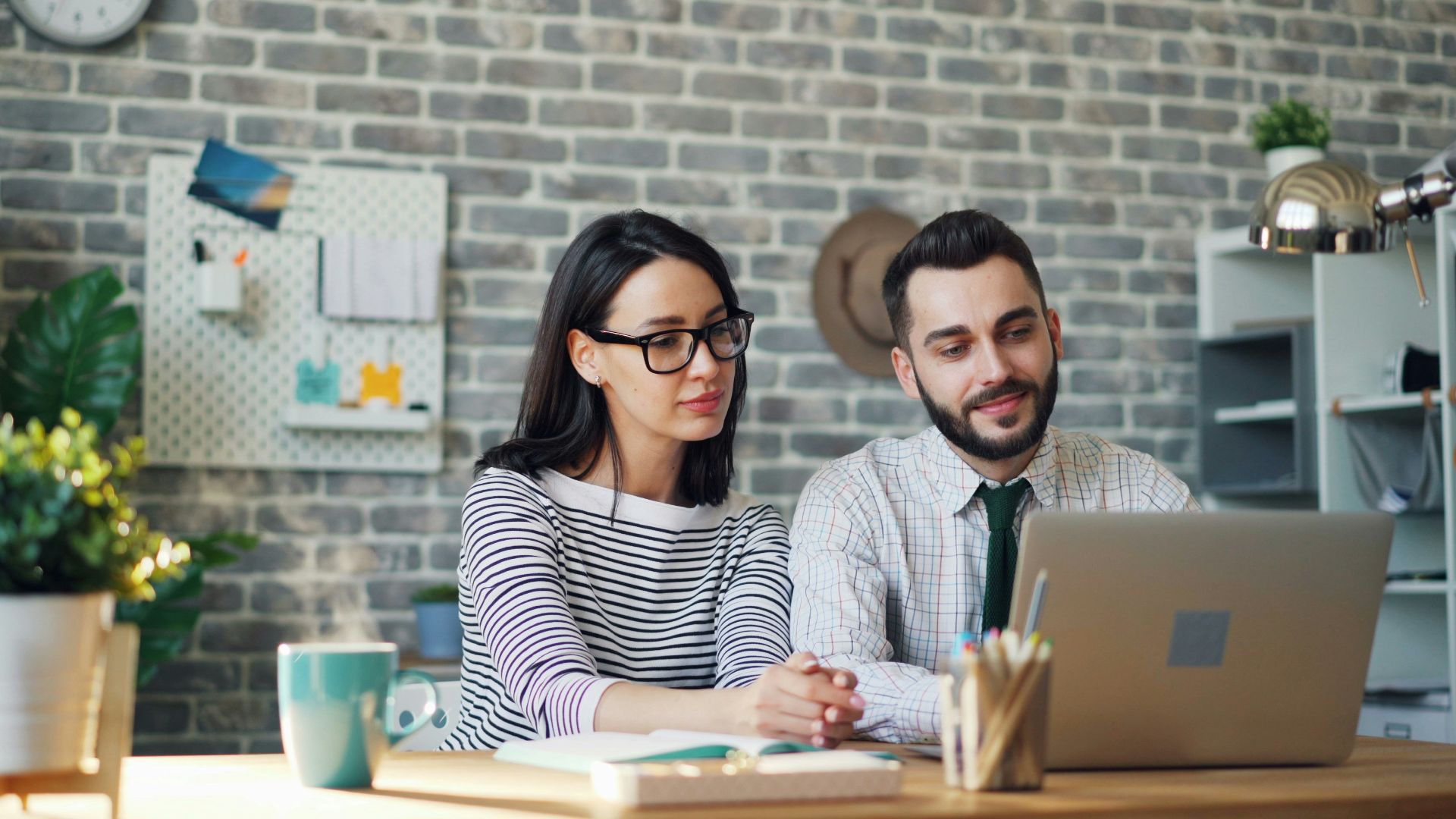 a man and woman sitting at a table looking at a laptop