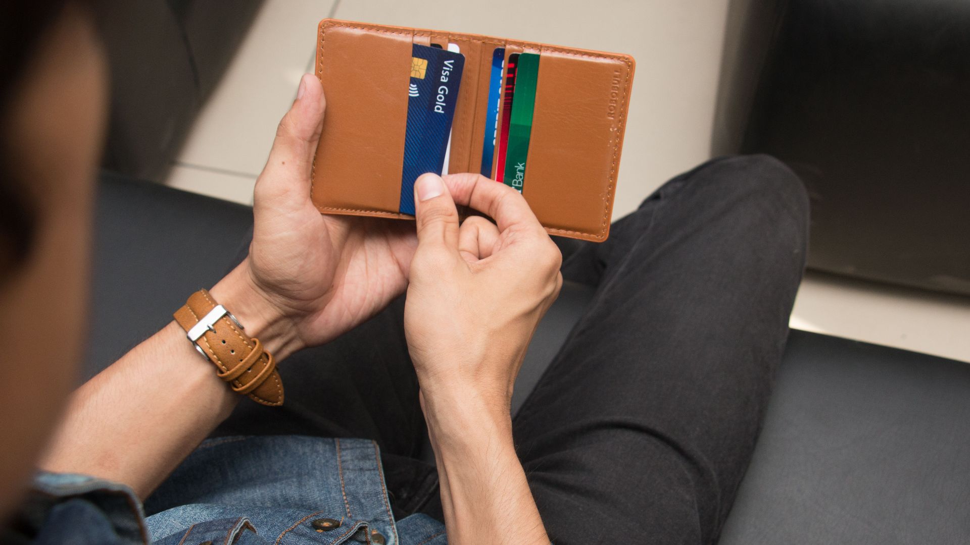 Close-up of a man holding a wallet with various credit cards, showcasing everyday finance essentials.