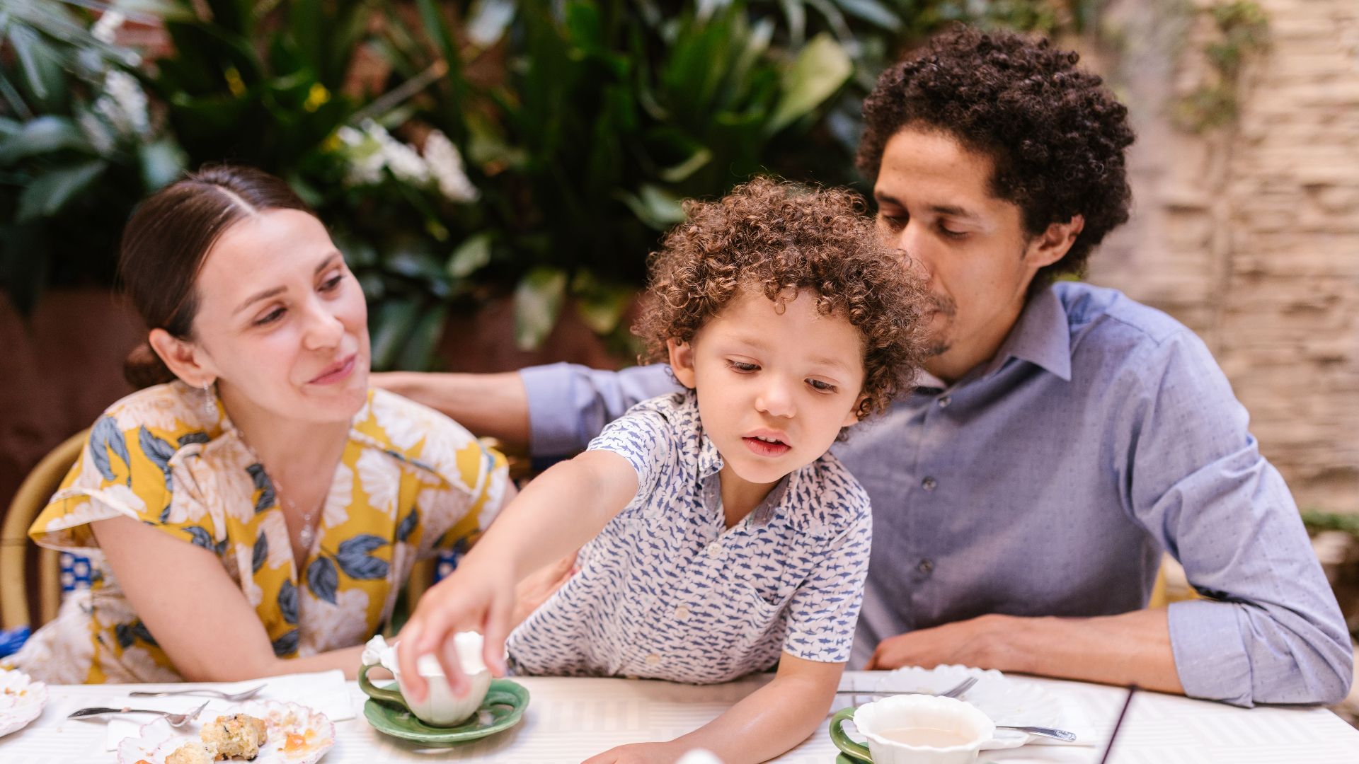 A family of three enjoying dessert and drinks at a cozy indoor cafe setting.