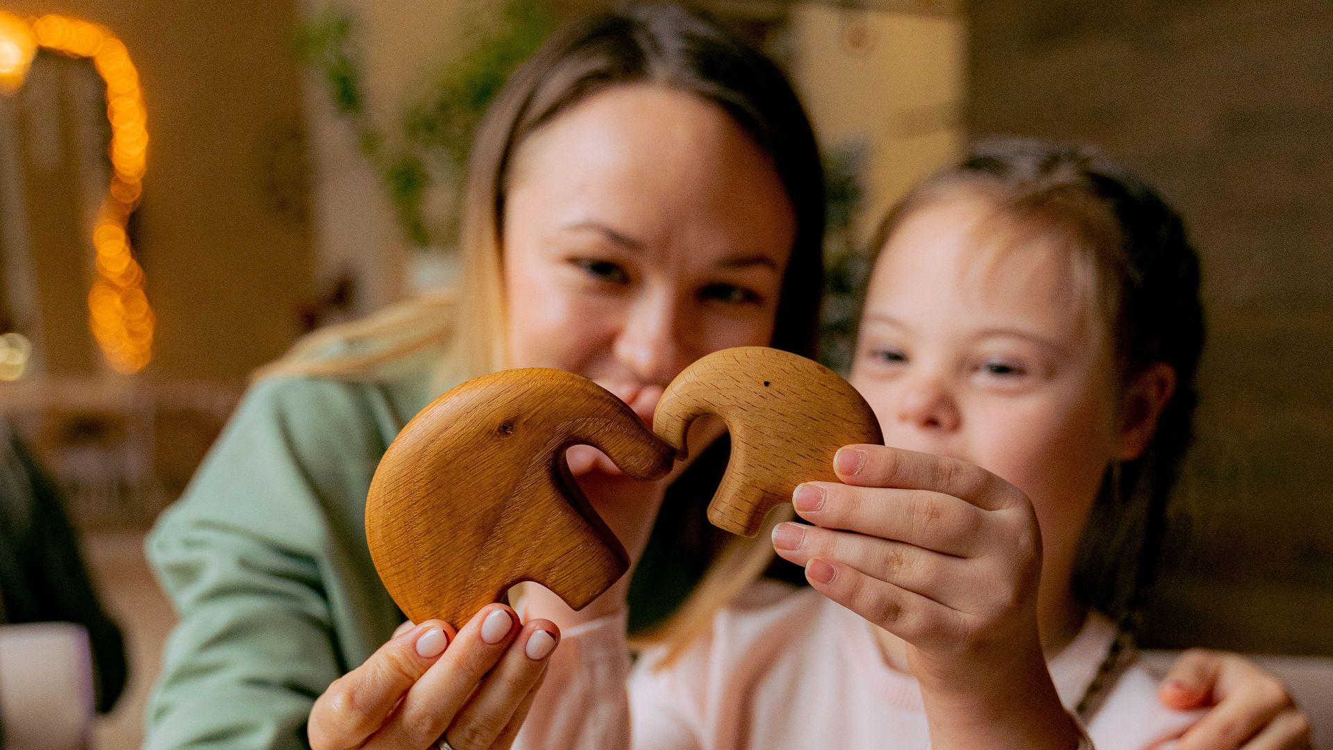 Smiling mother and daughter bonding while playing with wooden toys indoors.