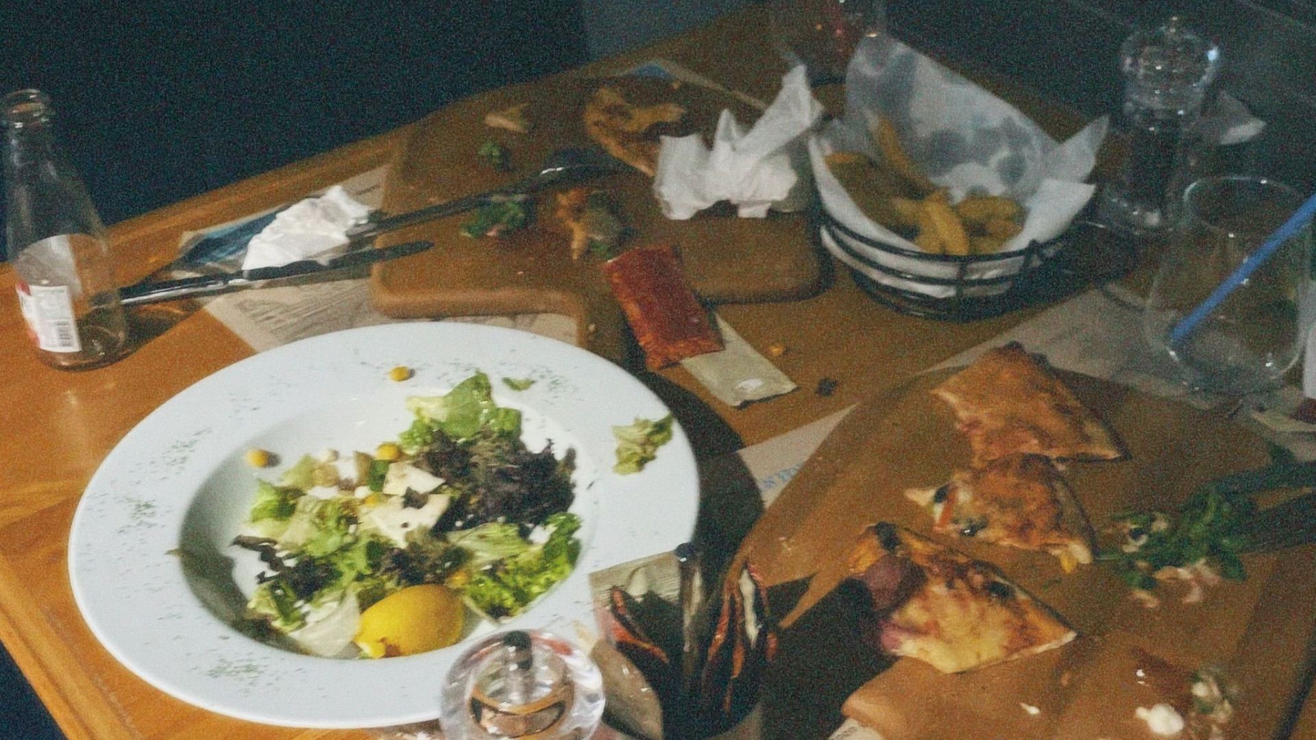 A cozy cafe table scene with remnants of a meal, including salad and appetizers.