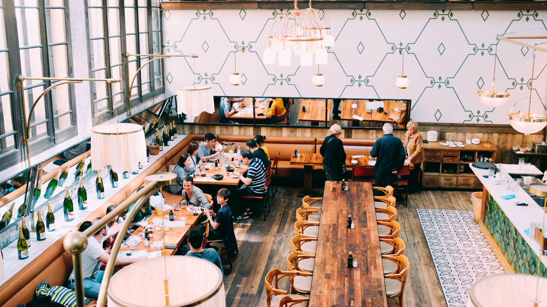 Spacious restaurant with stylish interior design, featuring wooden tables and a group of diners enjoying a meal.