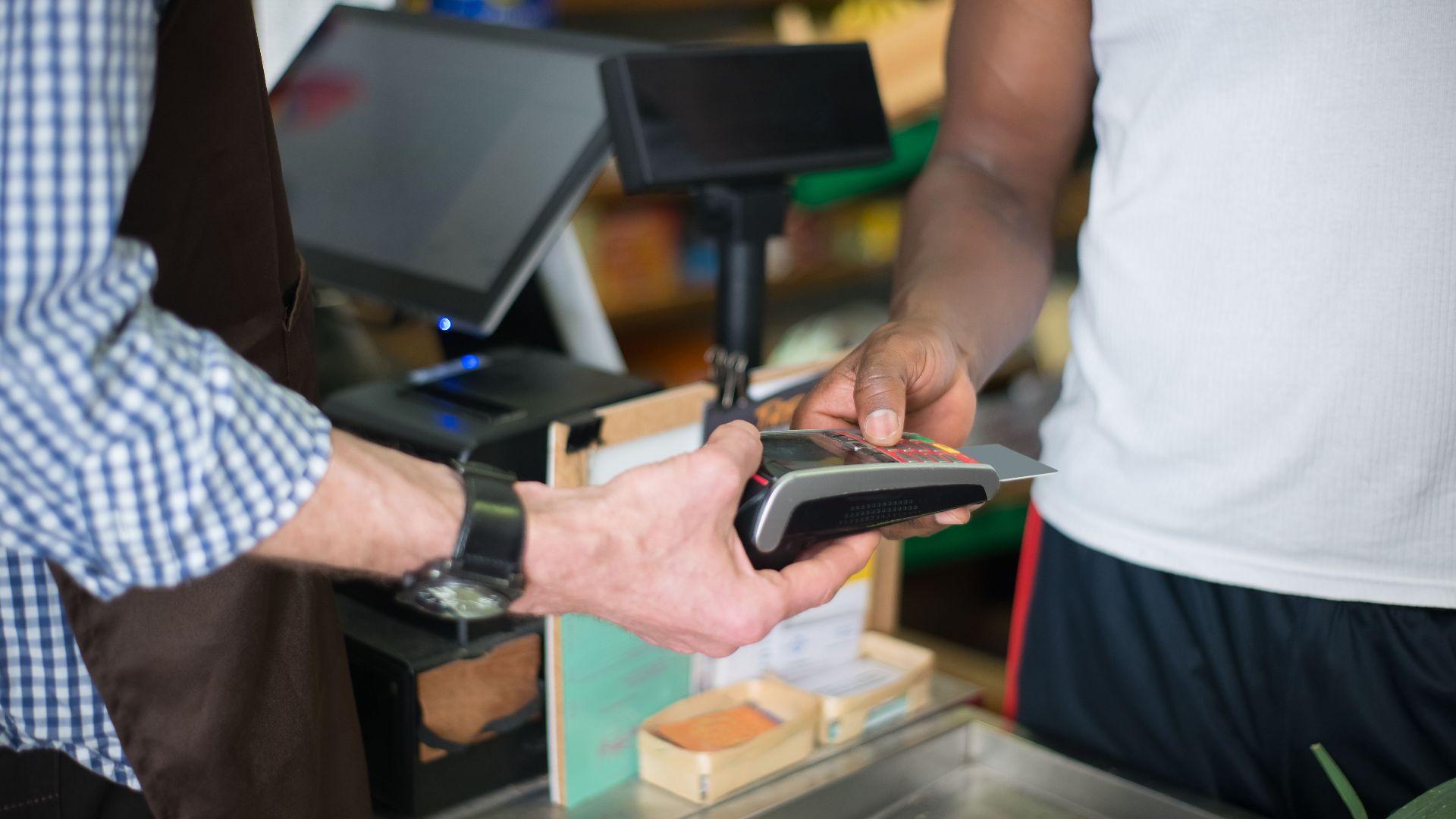 A customer making a payment with a credit card at a store checkout counter using a card reader.