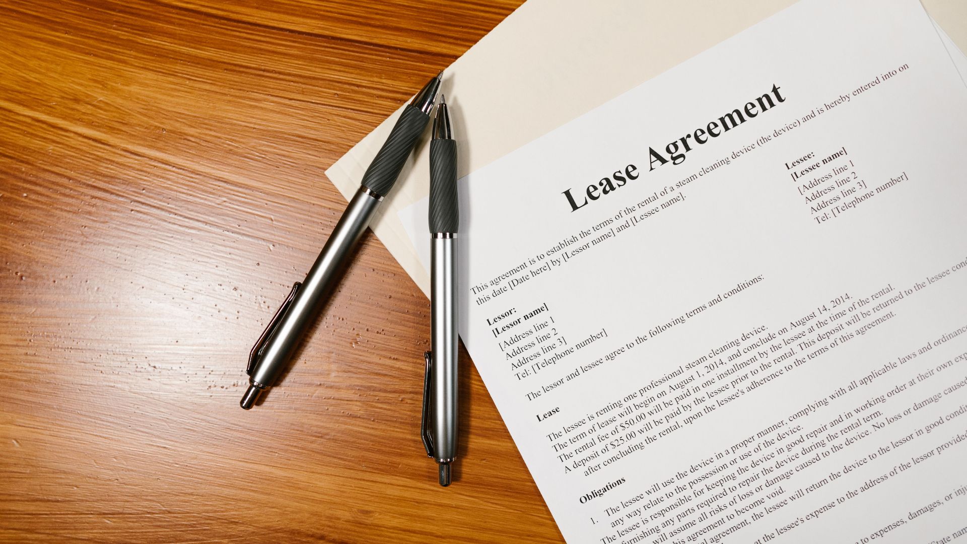 High-angle view of a lease agreement and pens on a wooden desk.