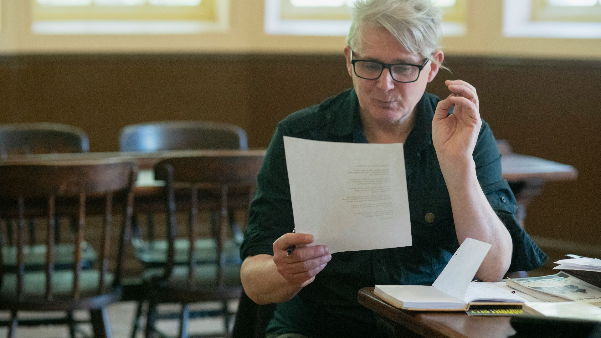 a man sitting at a table holding a piece of paper