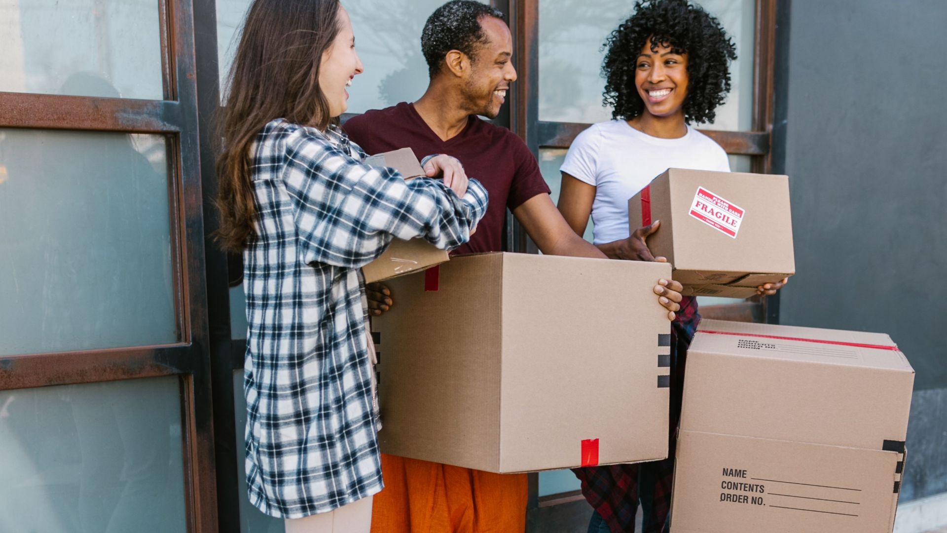 Young adults carry boxes into a modern apartment during their moving day.