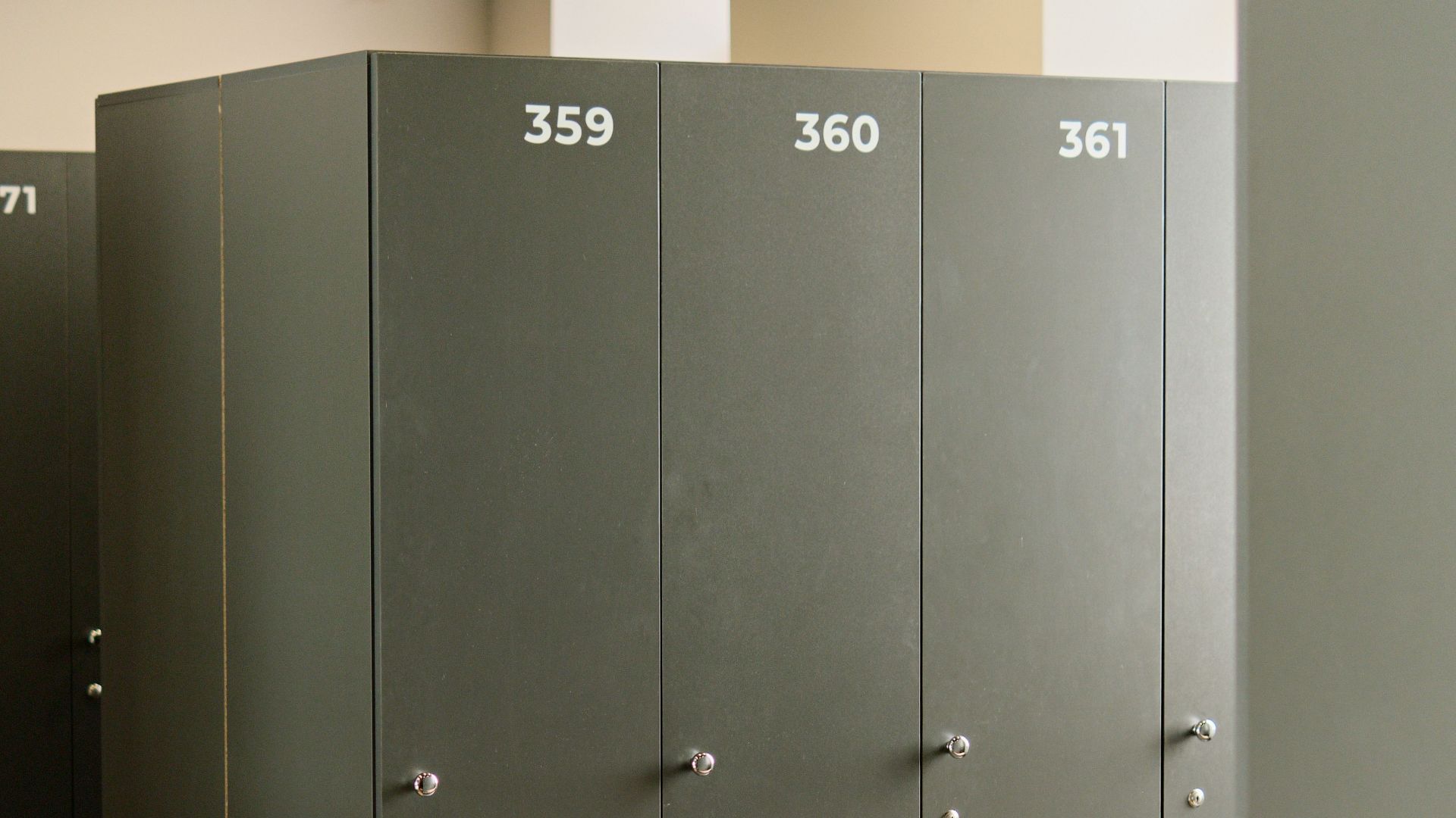 Spacious locker room featuring grey lockers and wooden benches, ideal for fitness centers.