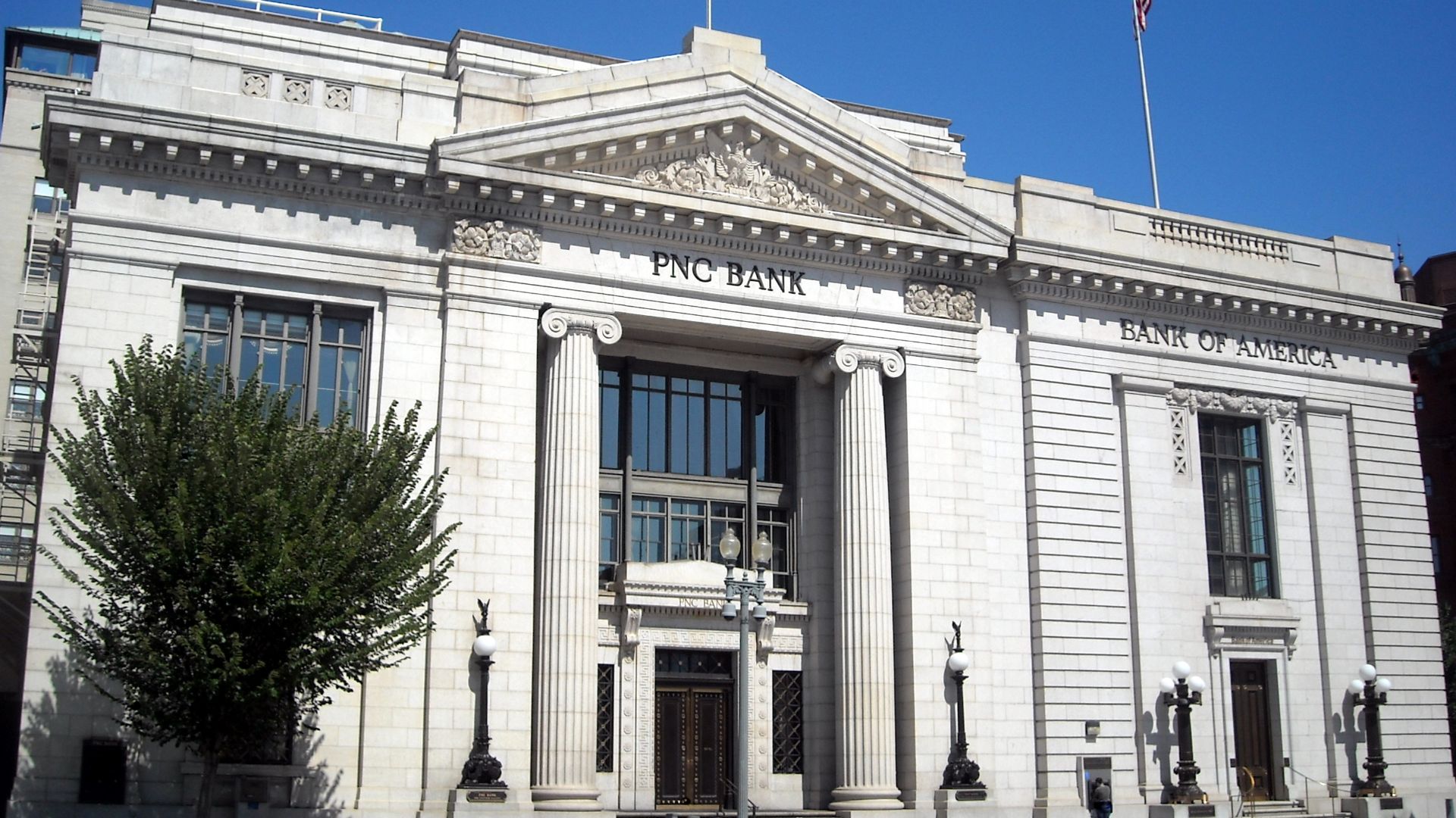 The left building is the former Riggs National Bank located at 1503-1505 Pennsylvania Avenue NW in downtown Washington, D.C. Construction of the Classical Revival style building was completed in 1902 to the designs of architectural firm York and Sawyer. T