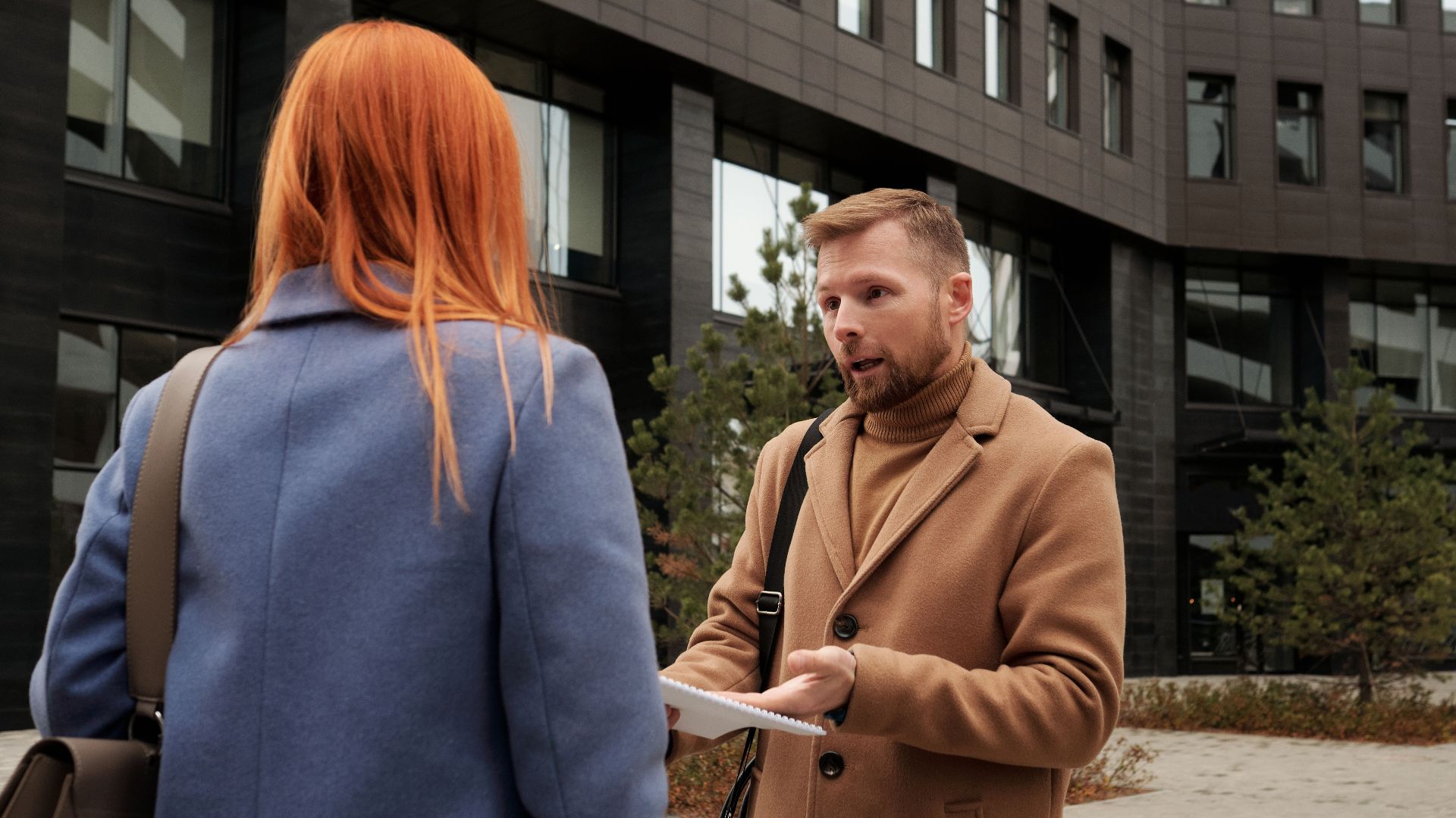 Two business professionals in conversation outside an urban office building.