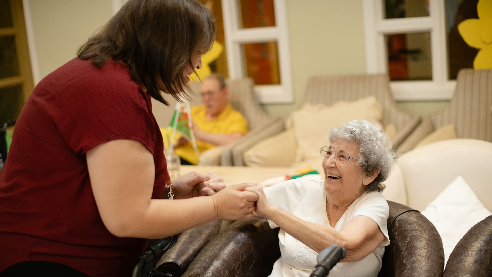 Caregiver assists elderly woman with walker.
