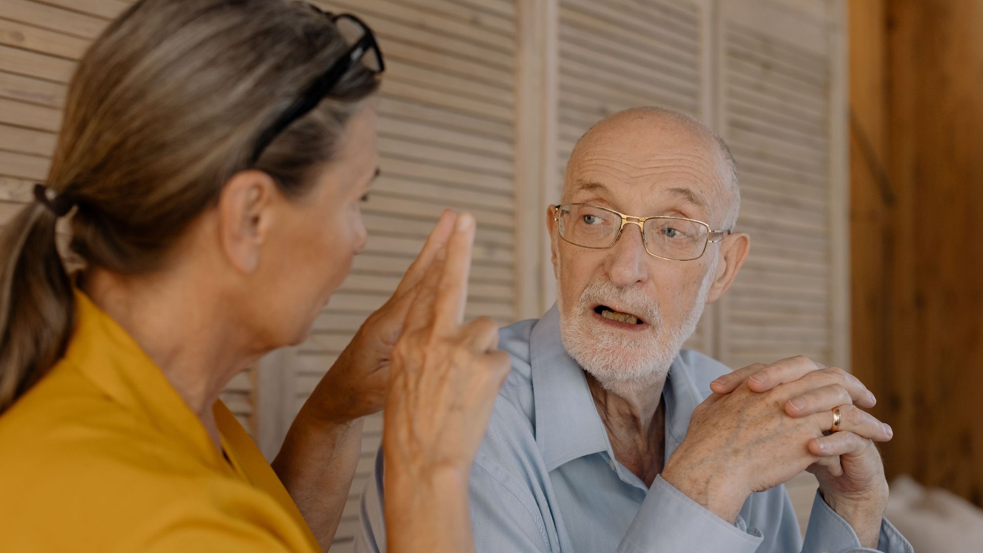 Elderly couple having an engaging conversation indoors, showcasing connection and emotion.