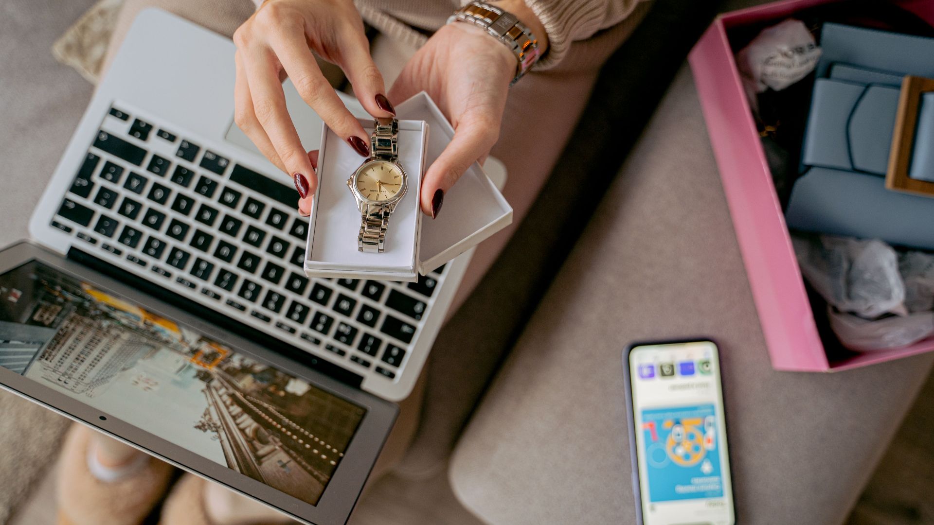 Woman unboxing a watch while online shopping using a laptop and smartphone. Perfect for lifestyle and technology themes.
