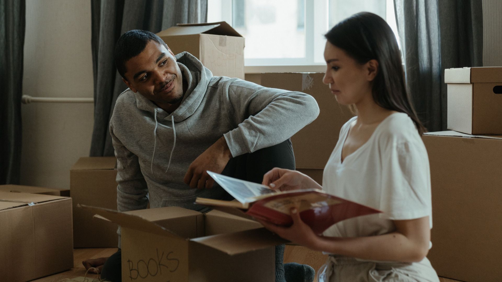 A couple exploring their new home while unpacking boxes and looking at a photo album.