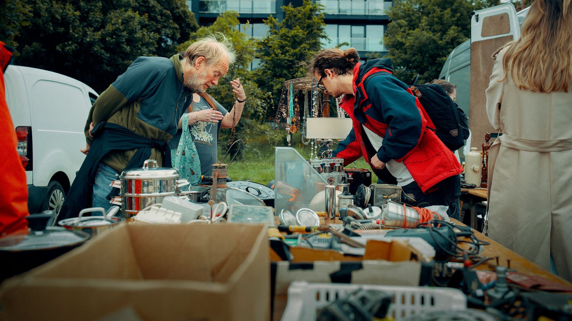 Two people examine goods at an outdoor market stall.