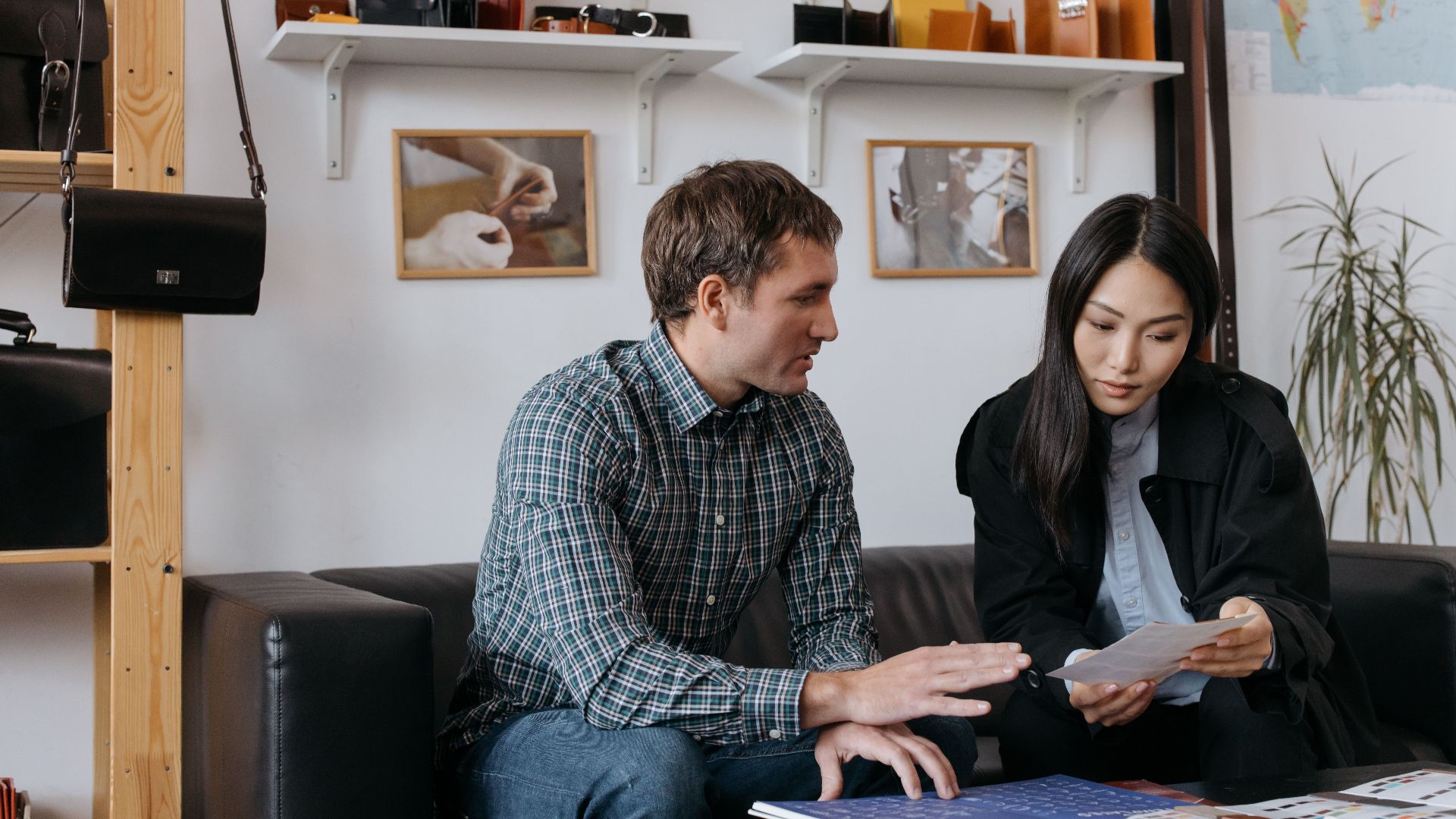 Asian woman and Caucasian man collaborate on fashion designs in an office setting.