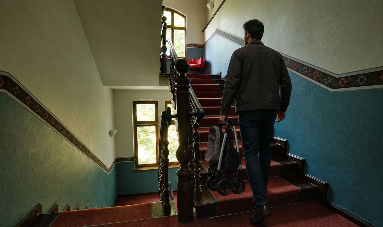 man carrying baby stroller upstairs