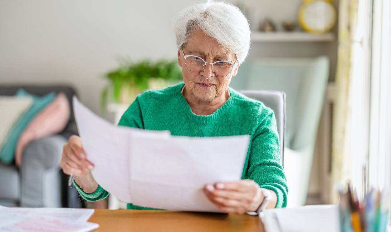 Senior woman sitting in the living room and doing paperwork
