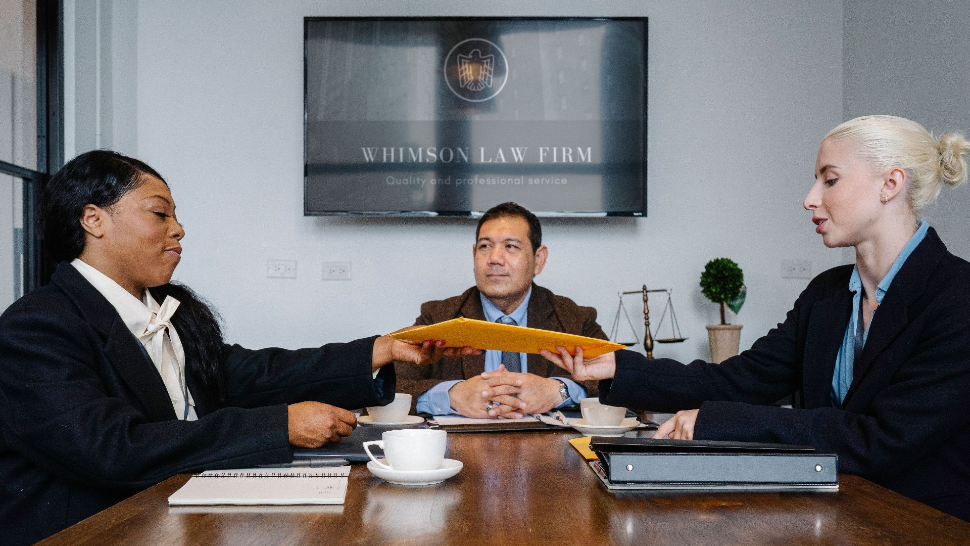 Group of cheerful diverse colleagues discussing court decision at table with notepad and cup