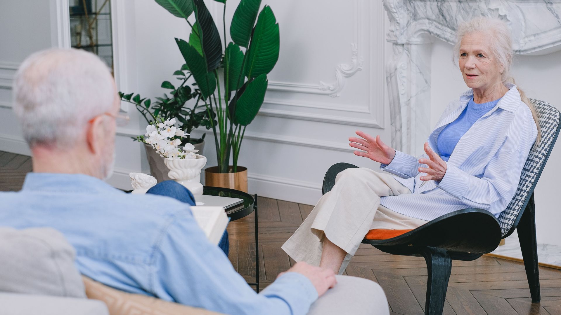 Elderly couple discussing in a stylish living room with plants.