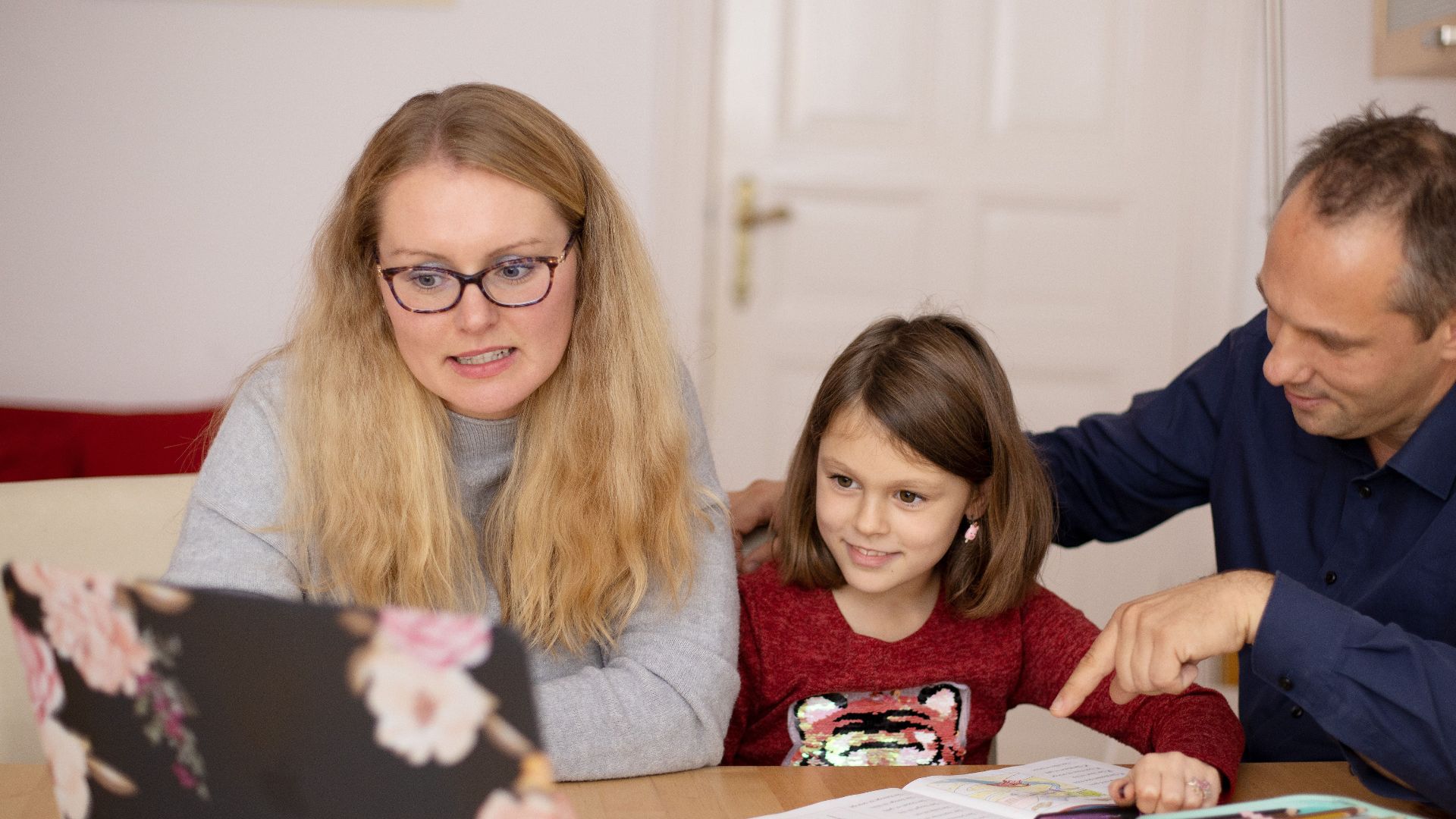 A family is engaged in homeschooling, using technology to learn together in a cozy home setting.