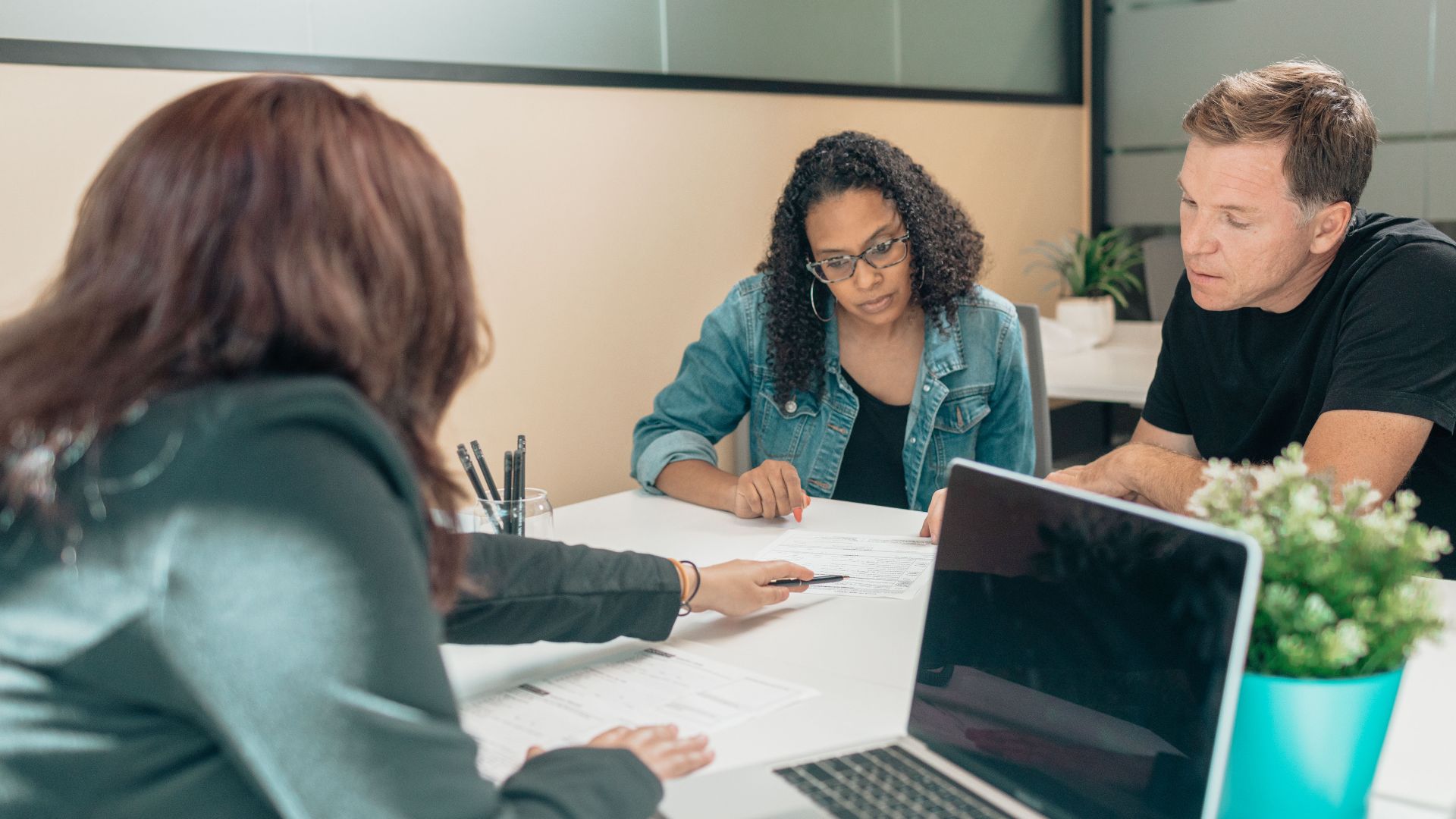Couple meeting with advisor for adoption process in a modern office setting.
