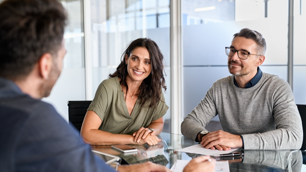 Smiling mature couple meeting with bank manager for investment