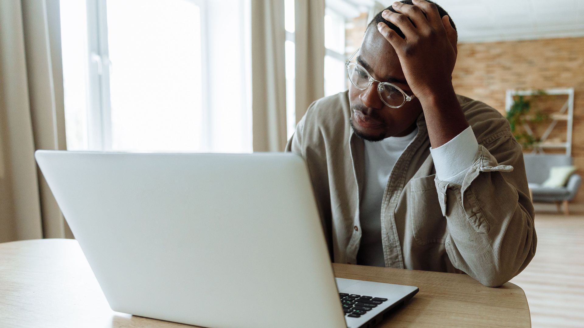 Man stressed while working on a laptop indoors, dealing with issues in remote work.