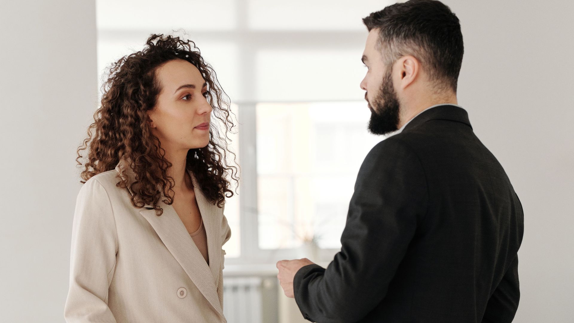 Two professionals engaged in a discussion in a bright, modern office setting.