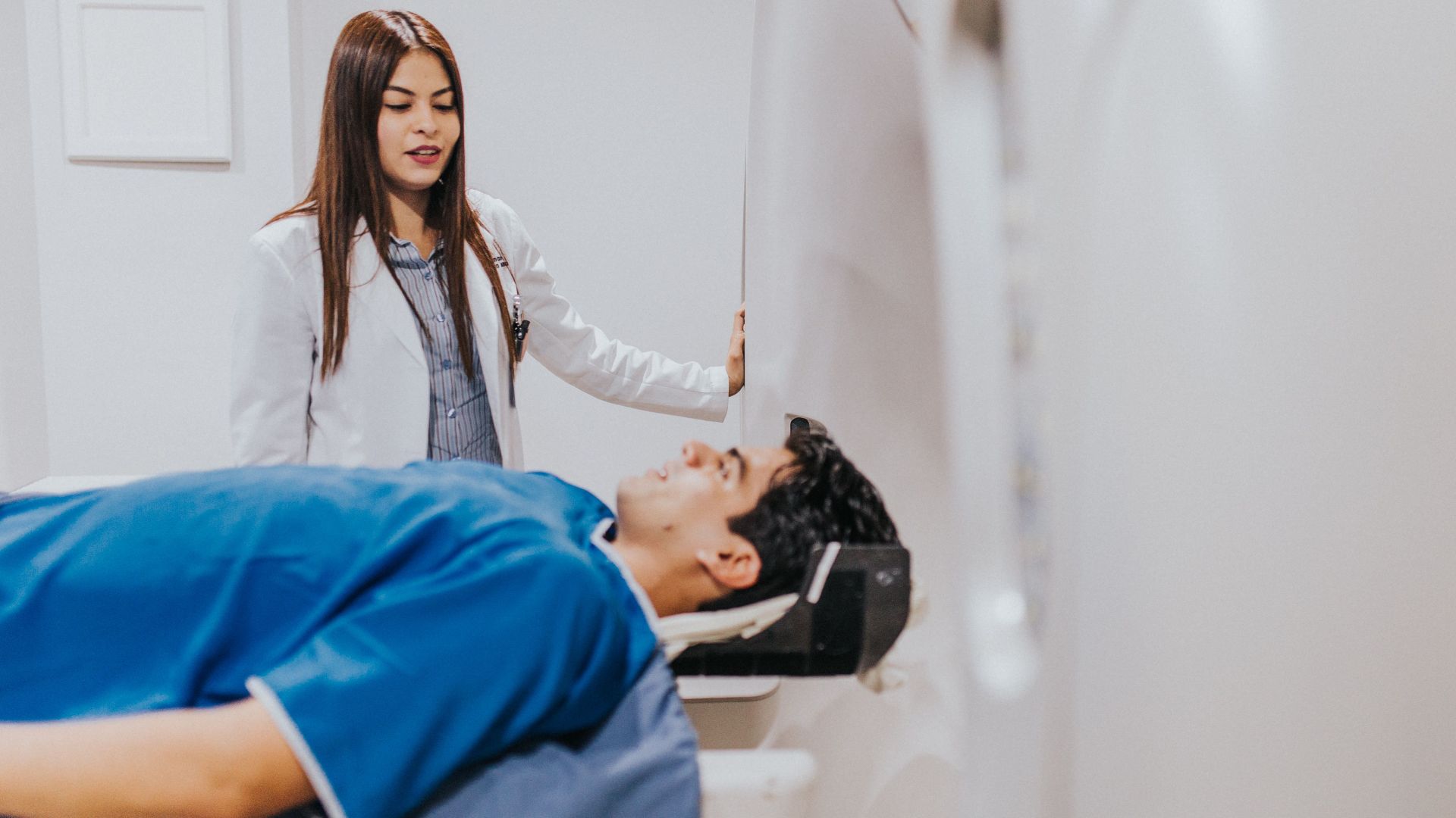 A doctor stands beside a patient in an MRI room, ensuring a smooth examination process.