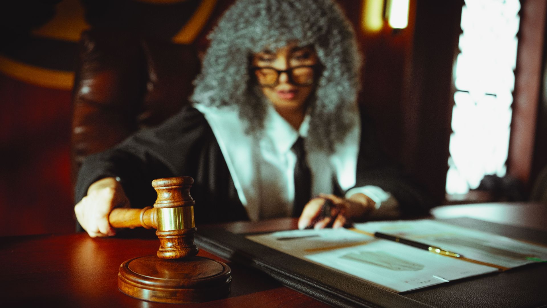 Female judge in a courtroom setting, focusing on legal documents with a gavel.