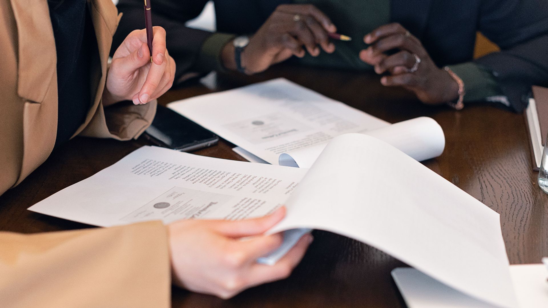 Close-up of professionals reviewing documents during a business meeting in an office setting.
