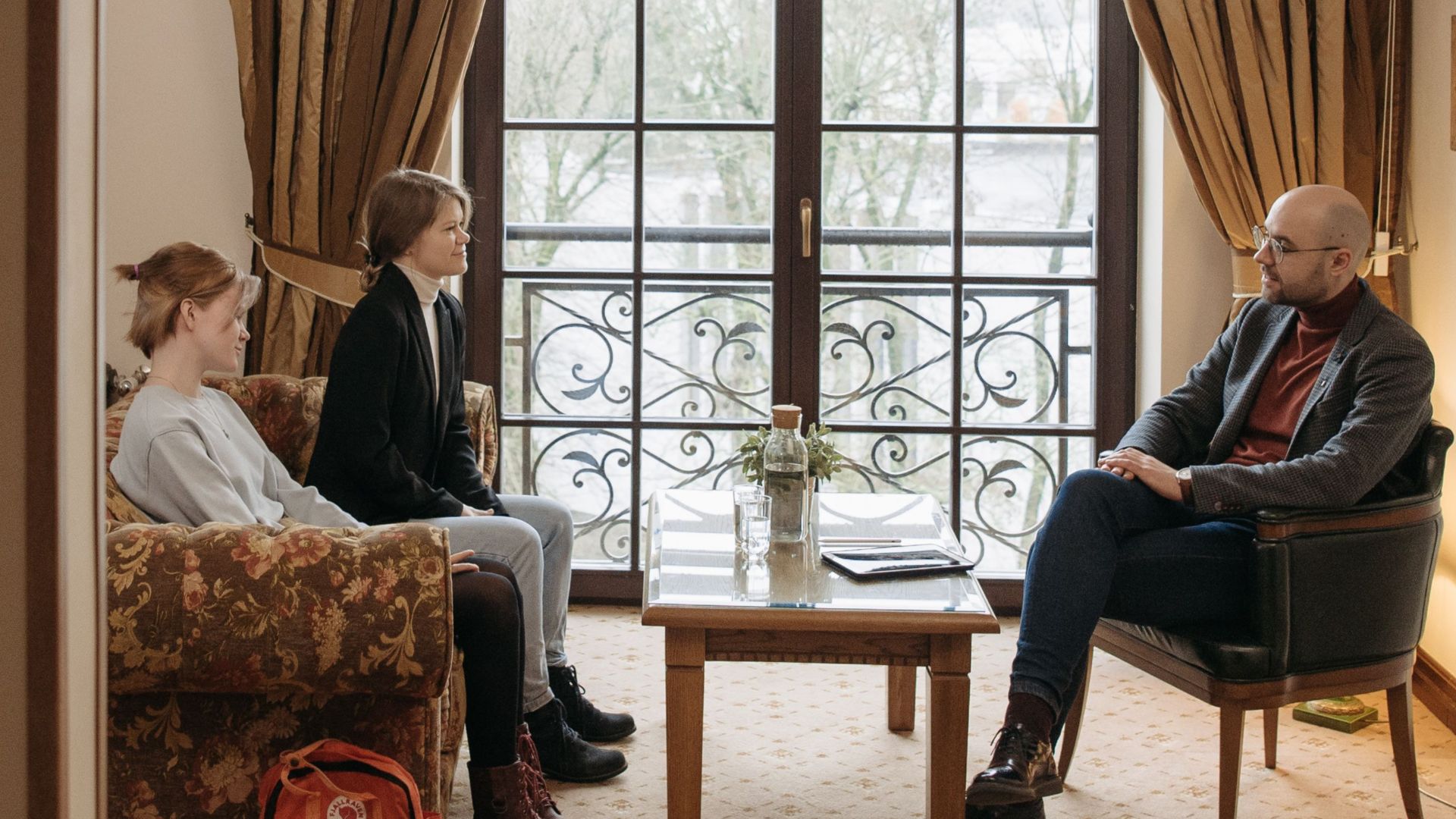 Counselor meeting with two clients in a warm, well-lit office setting.