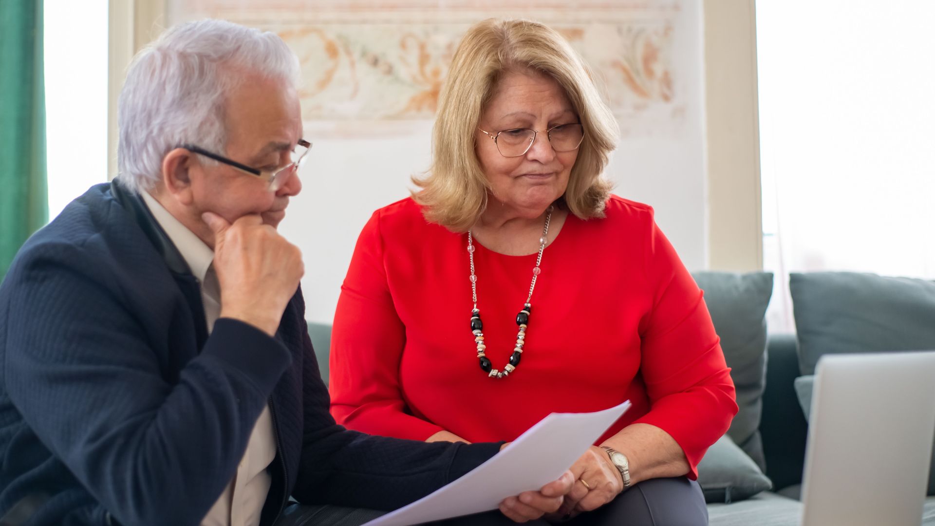 Elderly couple reviewing financial documents together at home in Portugal.