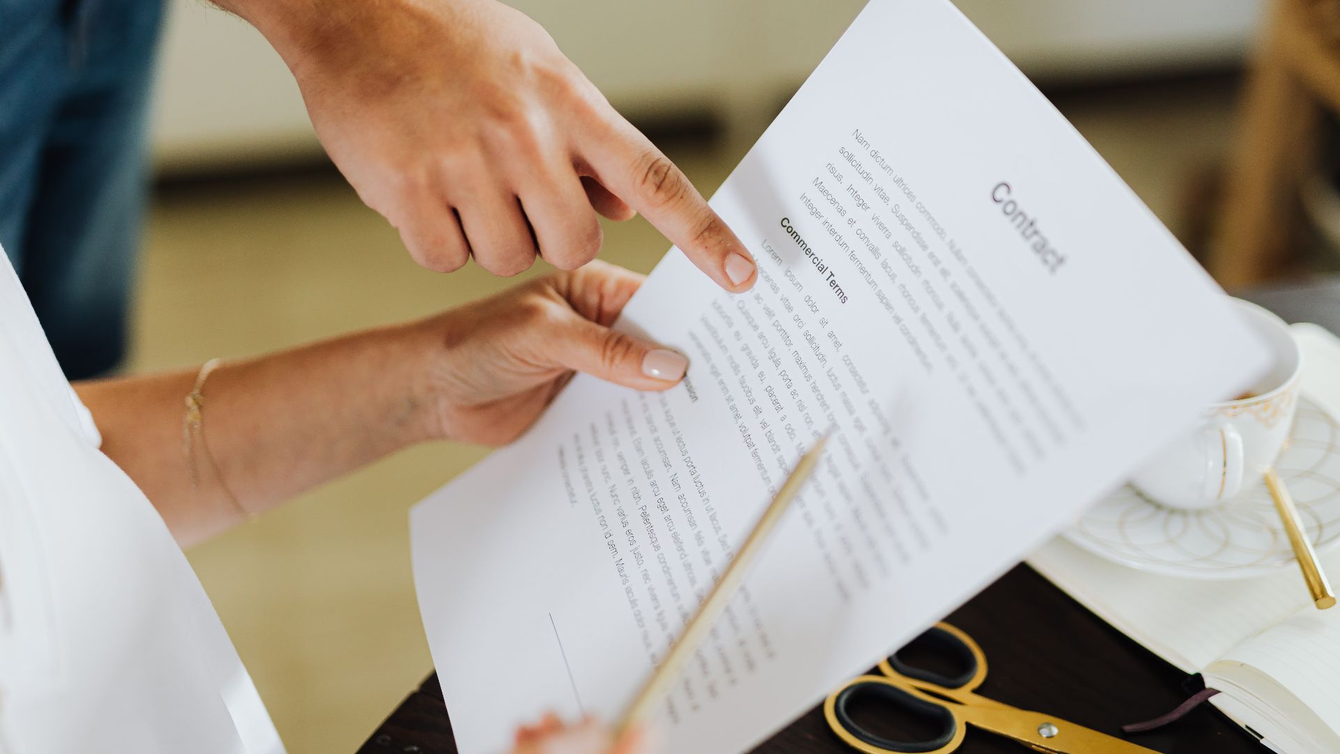 Close-up of two people discussing a business contract at a desk in an office setting.