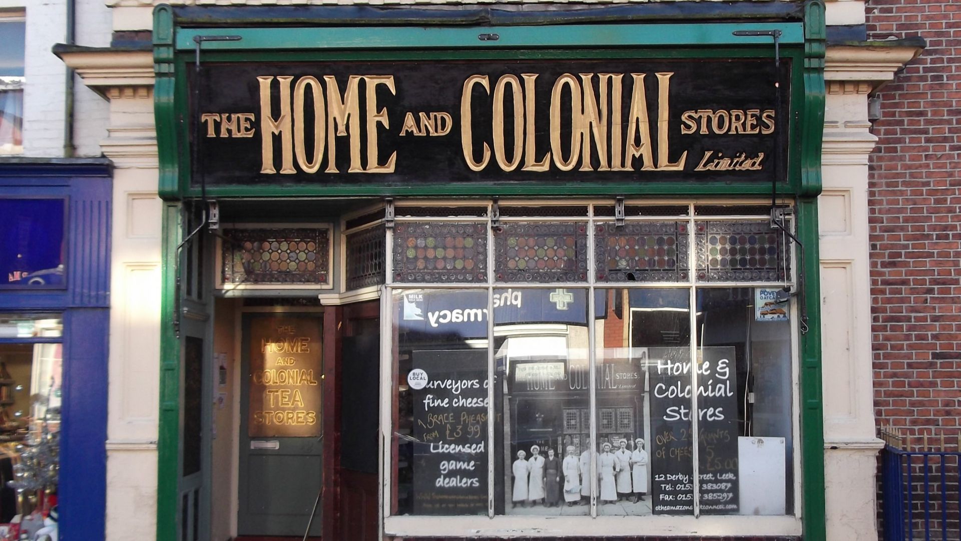 A shop front of the former Home and Colonial Stores chain at 12 Derby Street, Leek, Staffordshire. The photo in the window is not of this building at an earlier stage in its history: it's actually from the National Library of Ireland of a branch in Waterf