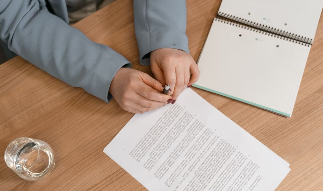 Hands reviewing documents on a wooden desk, ideal for business themes