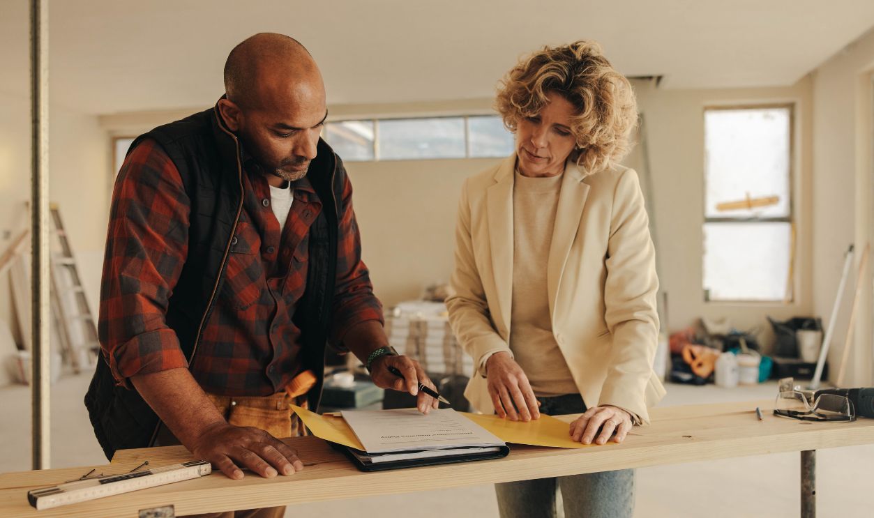 Mature contractor and homeowner signing a contract indoors for a home renovation project. They demonstrate professionalism and dedication to their work, ensuring a successful remodelling experience.