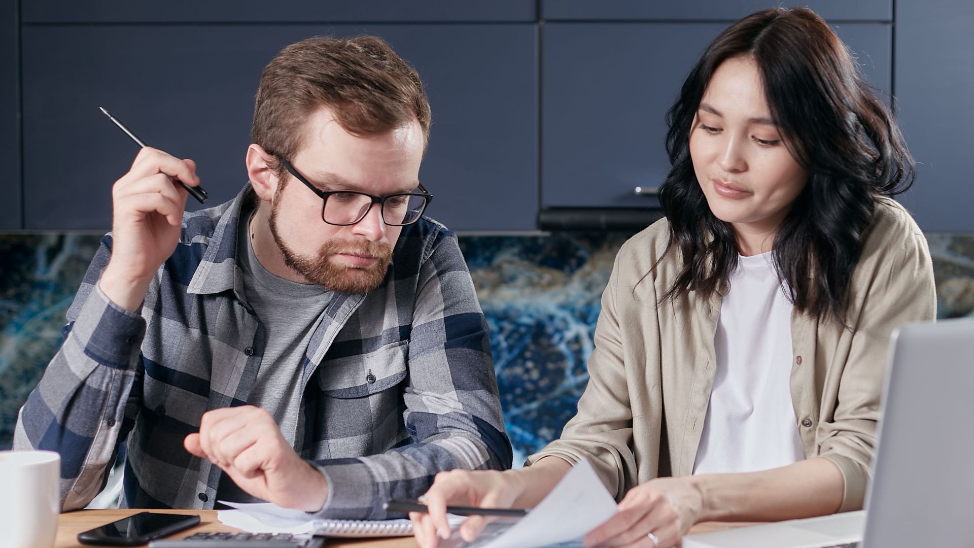A couple is reviewing and calculating their household bills together at home.