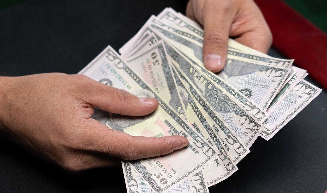 Close-up of hands counting dollar bills on a casino table with poker chips