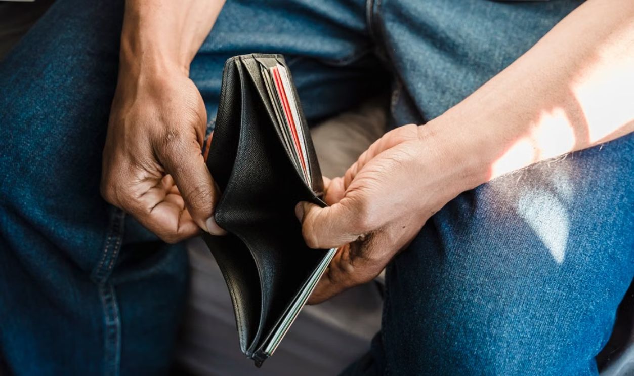 Close-up of a man holding an empty wallet, symbolizing financial crisis and hardship