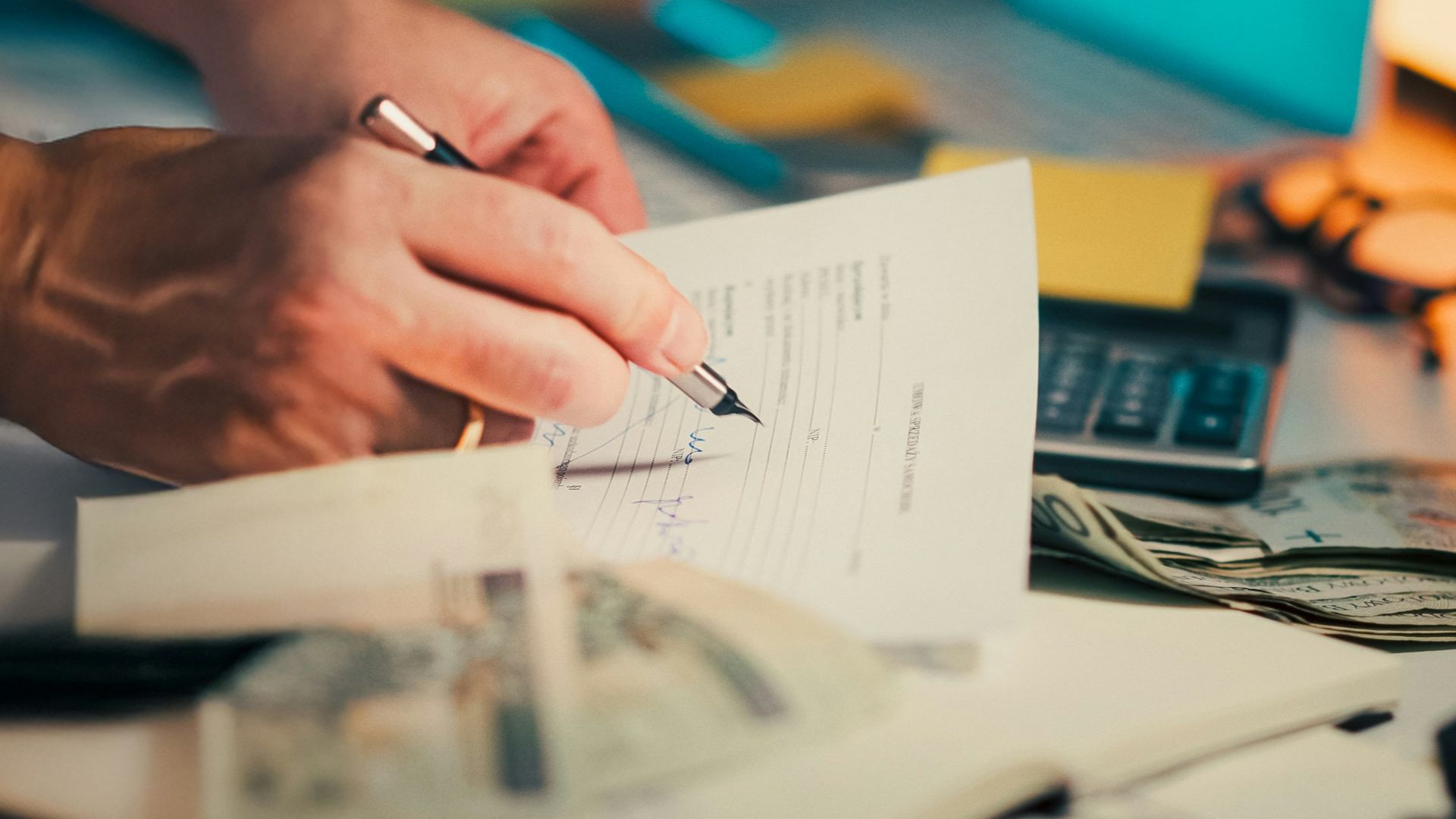 Hands signing a document on a desk.