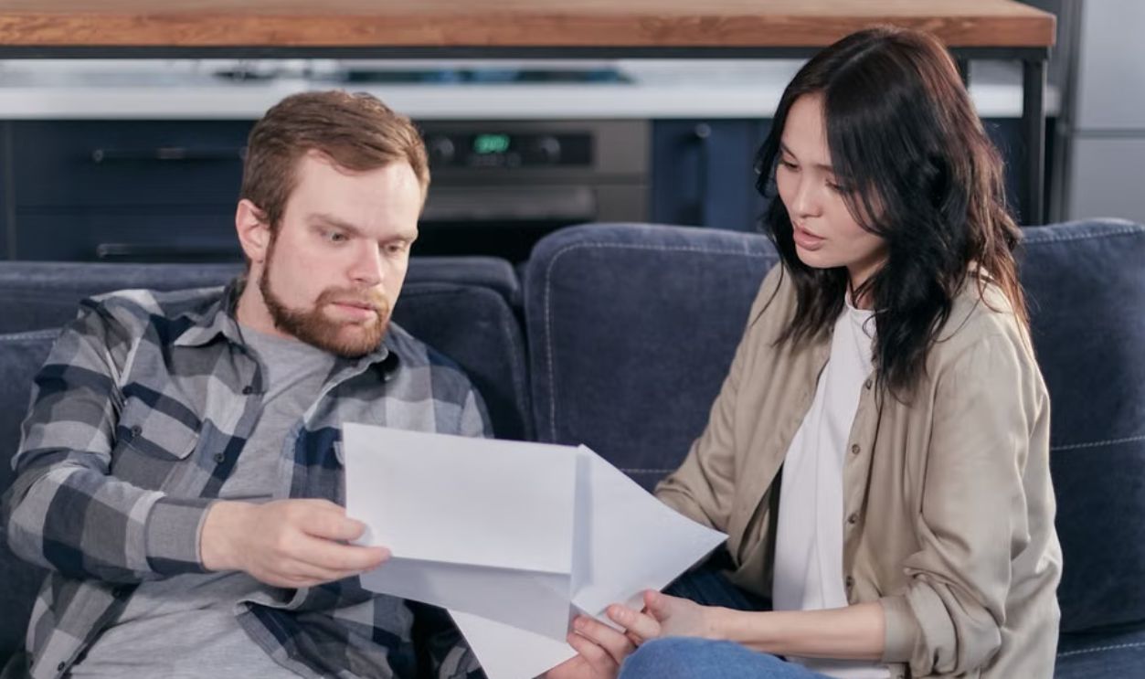 Asian woman and Caucasian man discussing taxes on couch