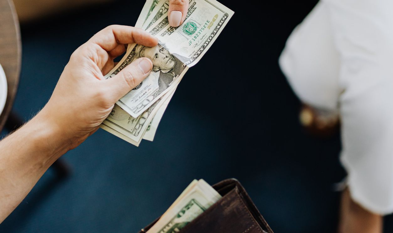 Close-up of hands exchanging cash, representing a financial transaction or payment