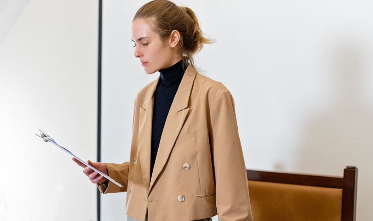 Caucasian woman in business attire evaluating a document in an indoor office setting