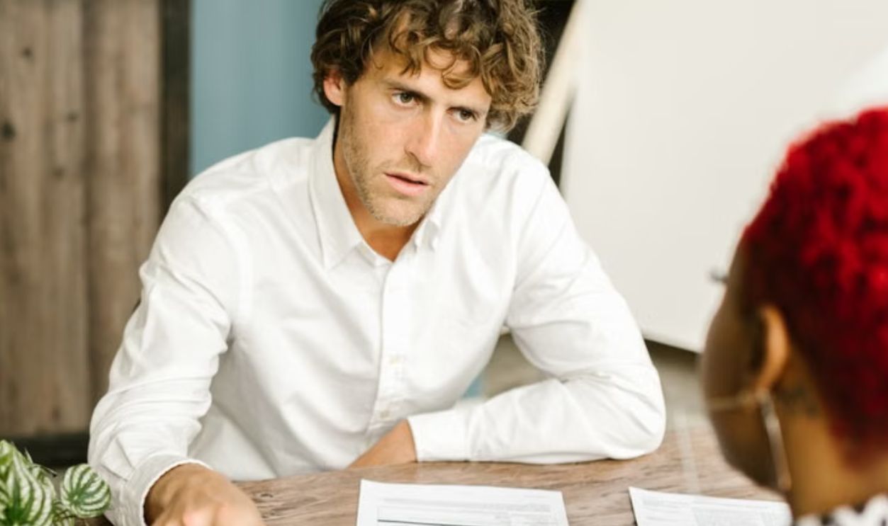 Business professionals discussing documents at a wooden table in an office setting