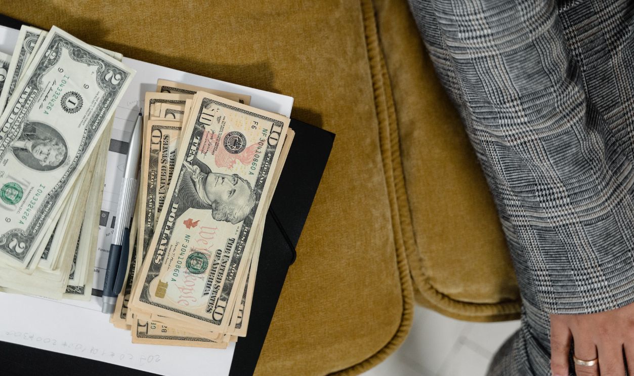 A close-up shot of US dollars on a couch, next to a plaid suit sleeve. Ideal for finance-related themes