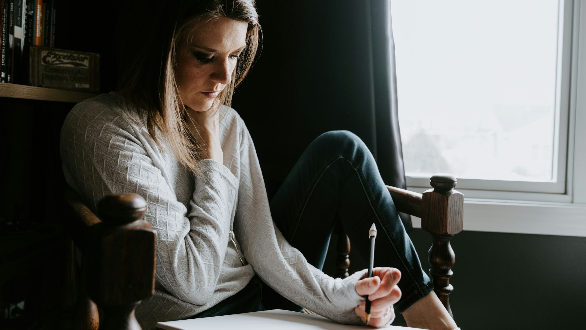 Woman sitting in chair writing in notebook